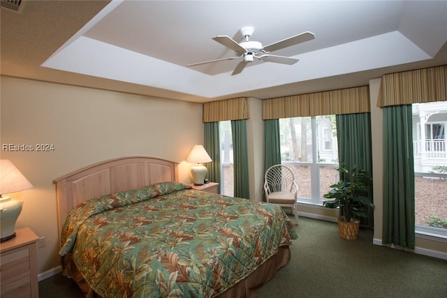 carpeted bedroom with ceiling fan and a raised ceiling