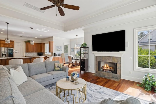 living room with crown molding, ceiling fan, a fireplace, and dark hardwood / wood-style flooring