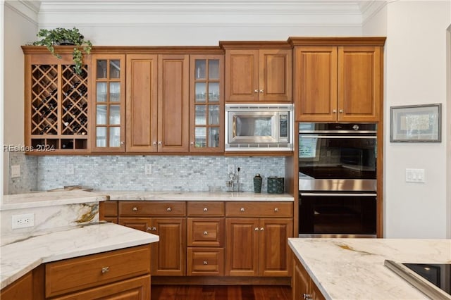 kitchen featuring dark wood-type flooring, crown molding, appliances with stainless steel finishes, light stone countertops, and decorative backsplash