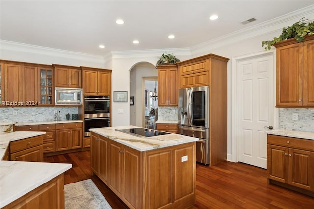 kitchen with crown molding, stainless steel appliances, a center island, and decorative backsplash