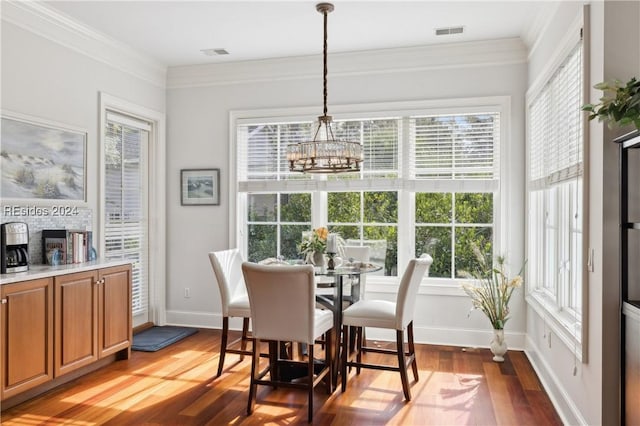 dining area featuring crown molding, a wealth of natural light, wood-type flooring, and a chandelier