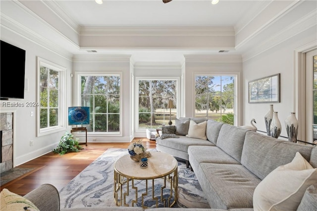 sunroom / solarium with a tiled fireplace, a raised ceiling, and a healthy amount of sunlight