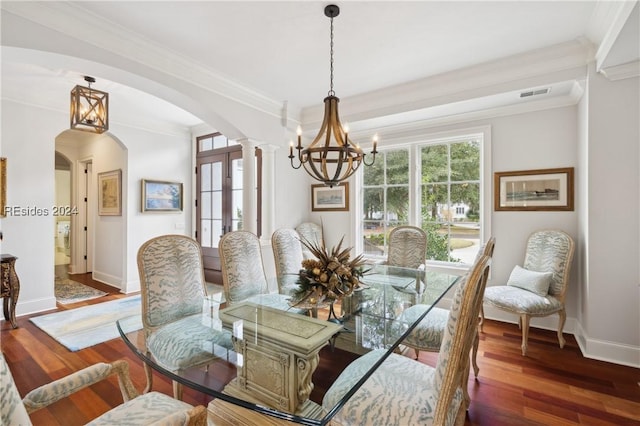 dining space featuring a notable chandelier, crown molding, dark hardwood / wood-style floors, and ornate columns