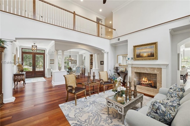 living room featuring dark hardwood / wood-style floors, a wealth of natural light, decorative columns, and a high ceiling