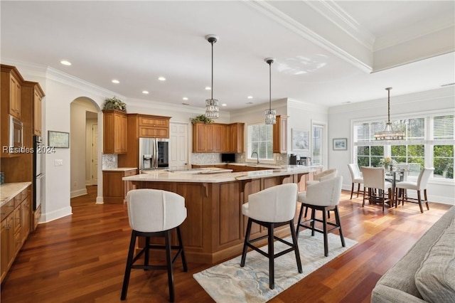 kitchen with a breakfast bar, decorative light fixtures, decorative backsplash, stainless steel appliances, and crown molding