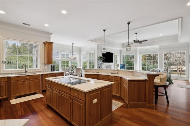 kitchen with sink, a breakfast bar area, a center island, black electric cooktop, and dark hardwood / wood-style flooring