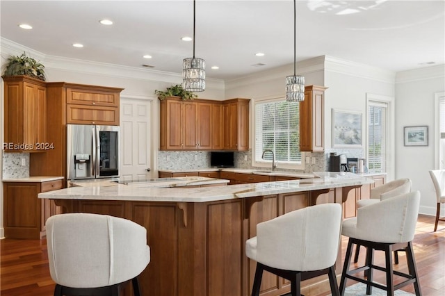 kitchen featuring a large island, pendant lighting, hardwood / wood-style floors, stainless steel refrigerator with ice dispenser, and tasteful backsplash