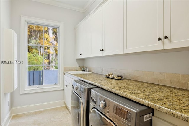 laundry area featuring cabinets, washing machine and dryer, sink, and ornamental molding