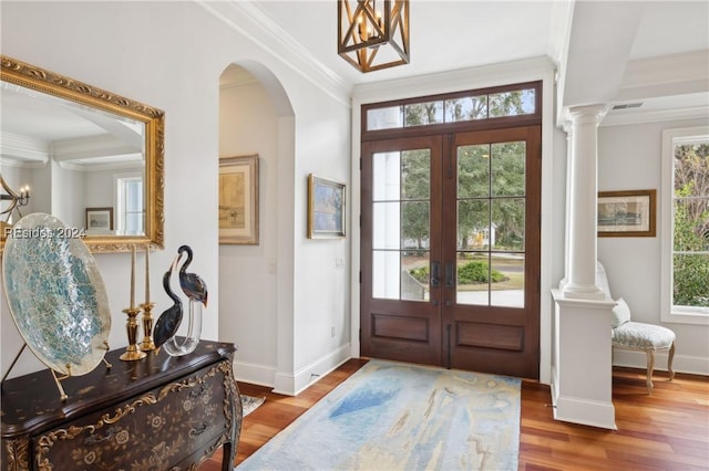 foyer entrance with hardwood / wood-style floors, crown molding, plenty of natural light, and french doors