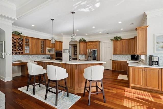 kitchen featuring crown molding, appliances with stainless steel finishes, decorative light fixtures, and a kitchen island