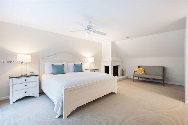 bedroom featuring ceiling fan, lofted ceiling, a fireplace, and light colored carpet