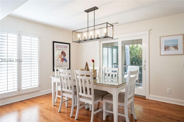 dining area with wood-type flooring and a chandelier