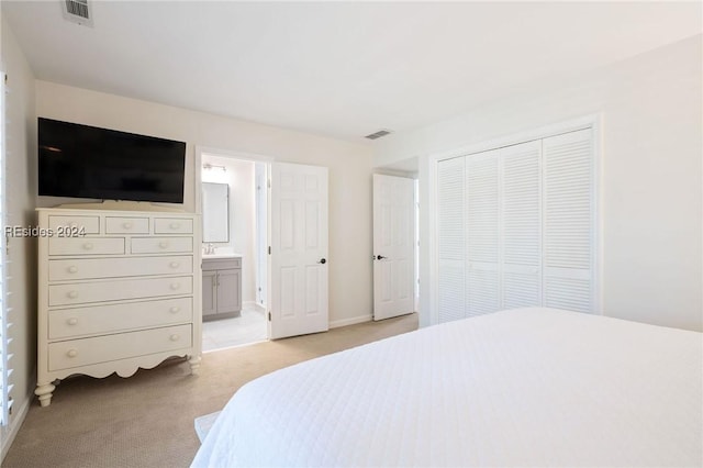 bedroom featuring light colored carpet, ensuite bath, and a closet