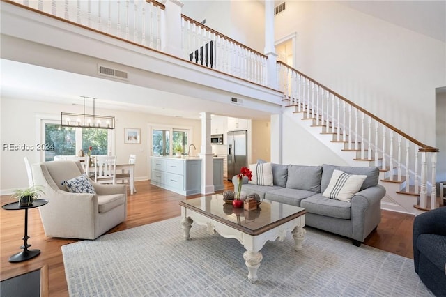 living room featuring a high ceiling, sink, a chandelier, and light hardwood / wood-style flooring