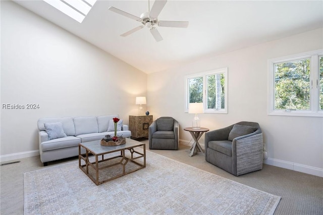 living room featuring ceiling fan, light colored carpet, lofted ceiling with skylight, and a wealth of natural light