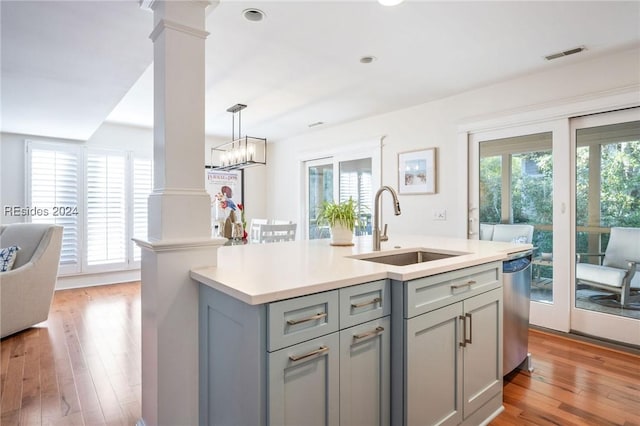 kitchen featuring plenty of natural light, an island with sink, sink, and ornate columns