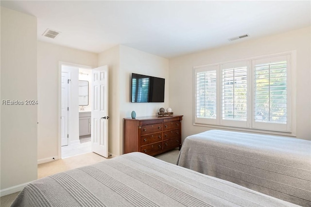 bedroom featuring light colored carpet and ensuite bath