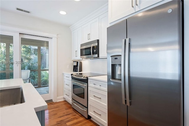 kitchen with appliances with stainless steel finishes, sink, white cabinets, and light wood-type flooring