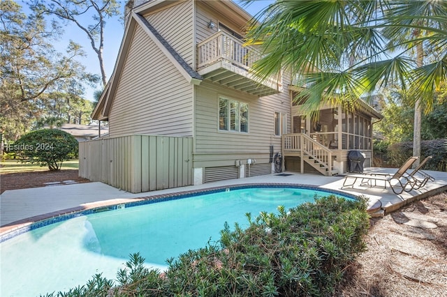 view of swimming pool featuring a patio area and a sunroom