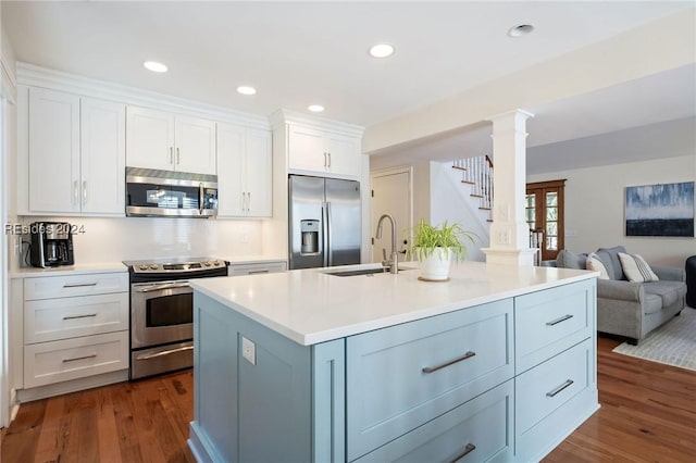 kitchen featuring sink, appliances with stainless steel finishes, white cabinetry, a kitchen island with sink, and dark hardwood / wood-style flooring