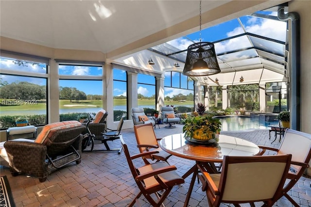 sunroom with a wealth of natural light, vaulted ceiling, and a water view