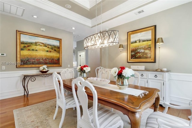 dining space featuring ornamental molding, light hardwood / wood-style floors, and a tray ceiling