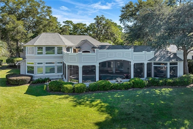 rear view of house featuring a sunroom and a lawn