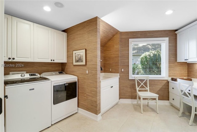 laundry area with light tile patterned floors, washer and clothes dryer, and cabinets