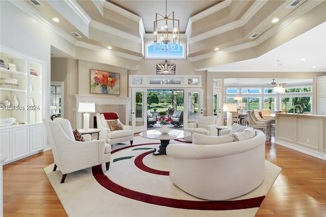 living room with a towering ceiling, ornamental molding, a chandelier, and light wood-type flooring