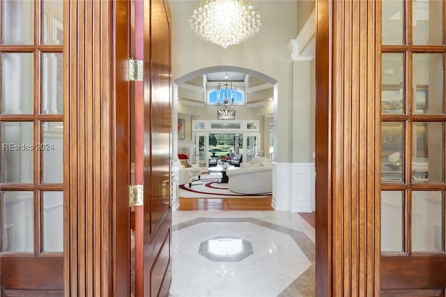 corridor featuring coffered ceiling and a notable chandelier