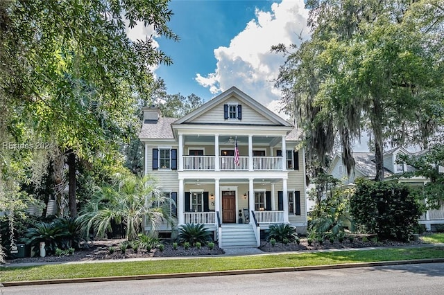 neoclassical home featuring a balcony and covered porch