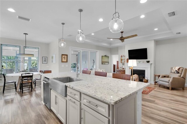 kitchen featuring a kitchen island with sink, pendant lighting, and a tray ceiling