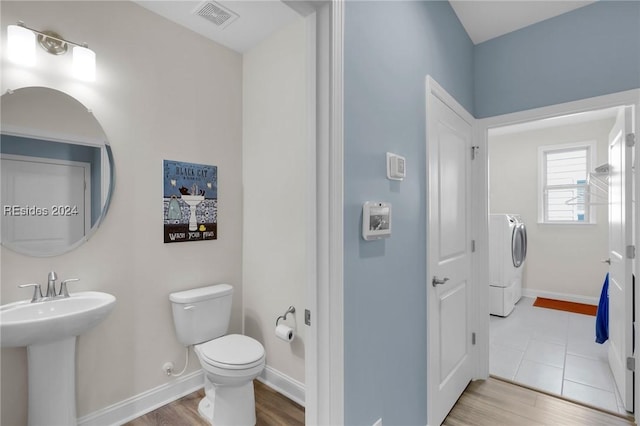 bathroom with hardwood / wood-style flooring, separate washer and dryer, sink, and toilet