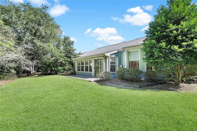 rear view of property featuring a sunroom and a lawn