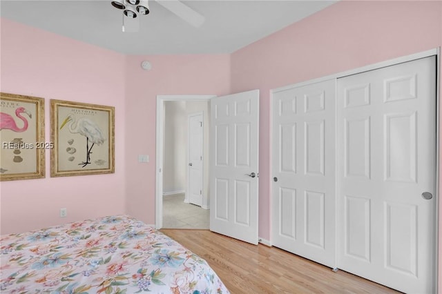 bedroom with light hardwood / wood-style floors, ceiling fan, and a closet