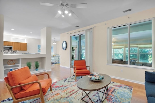 living room with ceiling fan, light hardwood / wood-style flooring, and built in features