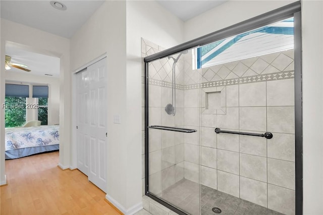 bathroom featuring ceiling fan, a shower with door, and hardwood / wood-style floors