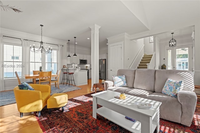 living room featuring crown molding, a wealth of natural light, a notable chandelier, and light wood-type flooring