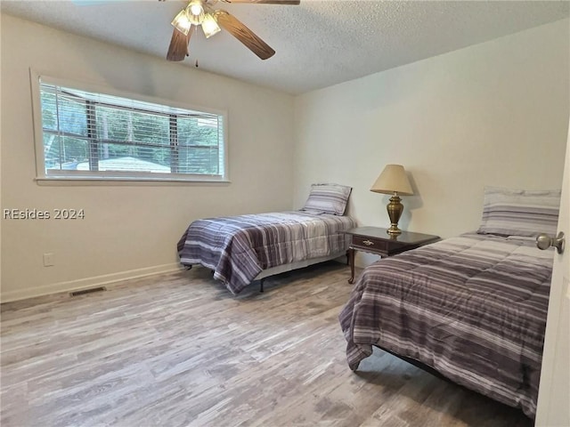 bedroom with ceiling fan, light hardwood / wood-style flooring, and a textured ceiling