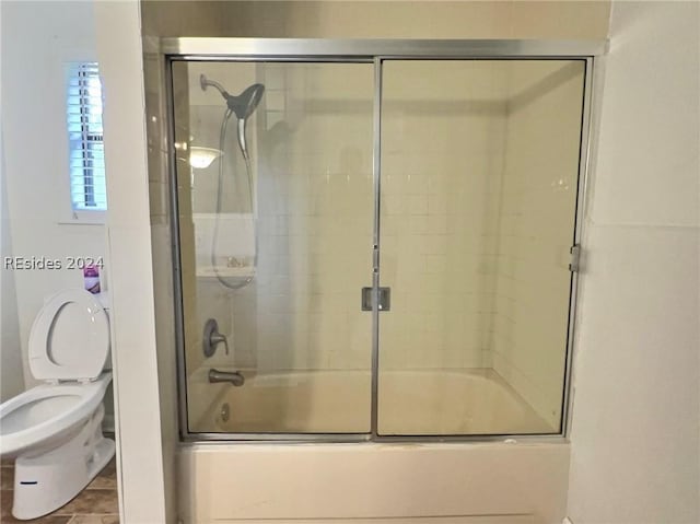 bathroom with enclosed tub / shower combo and toilet