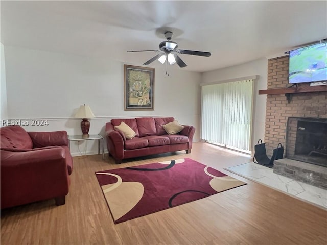 living room with ceiling fan, light hardwood / wood-style floors, and a brick fireplace