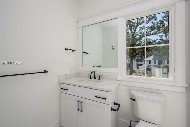 bathroom featuring vanity, plenty of natural light, and toilet