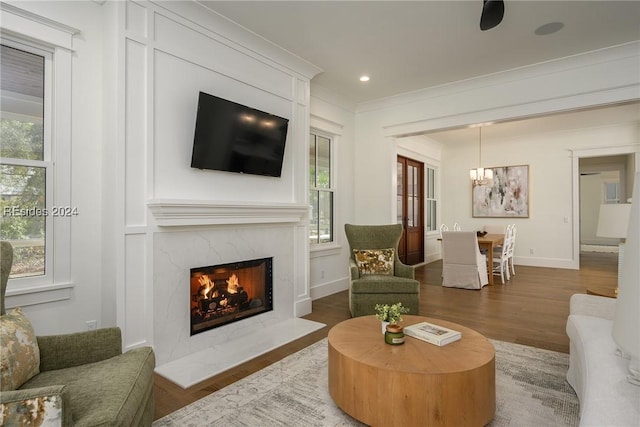 living room with a notable chandelier, a premium fireplace, ornamental molding, and dark hardwood / wood-style floors