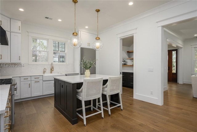 kitchen with a kitchen island, pendant lighting, sink, white cabinets, and dark hardwood / wood-style flooring