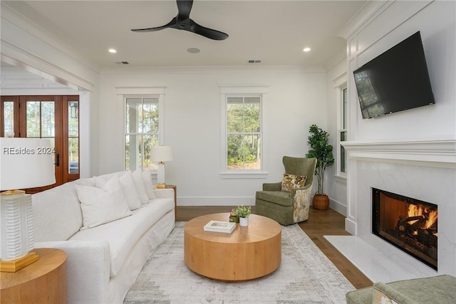 living room with hardwood / wood-style floors, crown molding, a fireplace, and ceiling fan