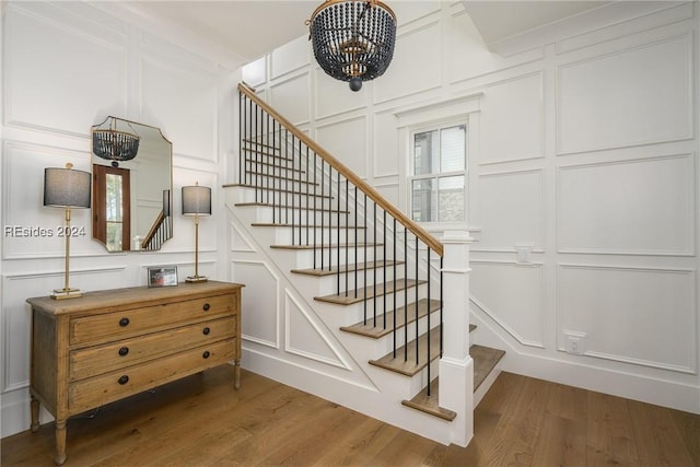 staircase with hardwood / wood-style flooring and a chandelier