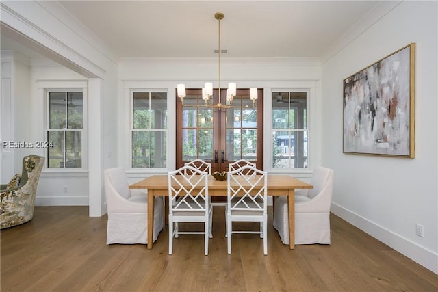 dining room featuring hardwood / wood-style floors, crown molding, french doors, and a chandelier