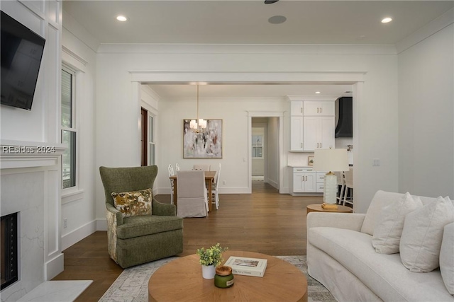 living room with a notable chandelier, crown molding, a fireplace, and wood-type flooring