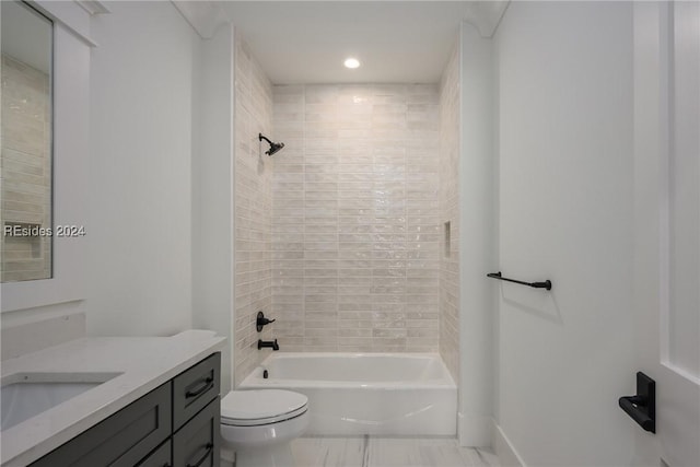 full bathroom featuring tiled shower / bath, vanity, and toilet