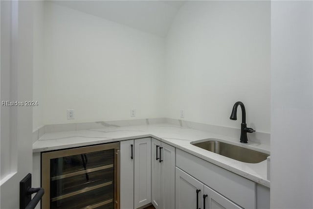 kitchen with light stone counters, beverage cooler, and sink